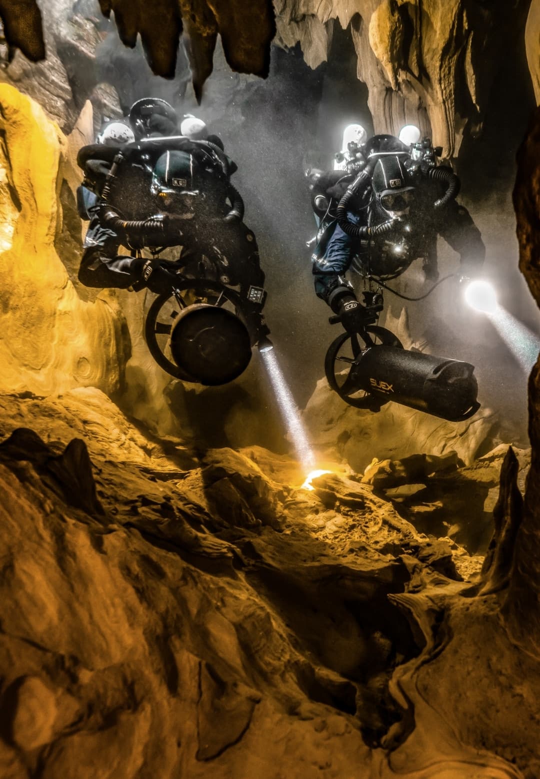 Due subacquei con DPV SUEX esplorano una grotta sommersa con le torce accese